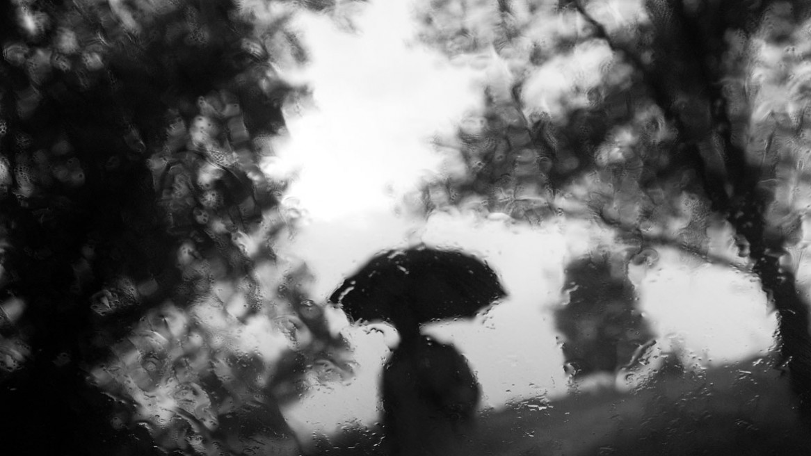 vue depuis une fenêtre humide, une silhouette sous un parapluie s'approche. Photo Matthieu Dupont