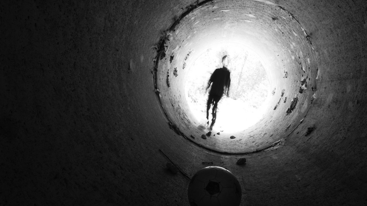Un ballon posé dans un tunnel et un enfant à la silhouette étrange qui s'en approche.