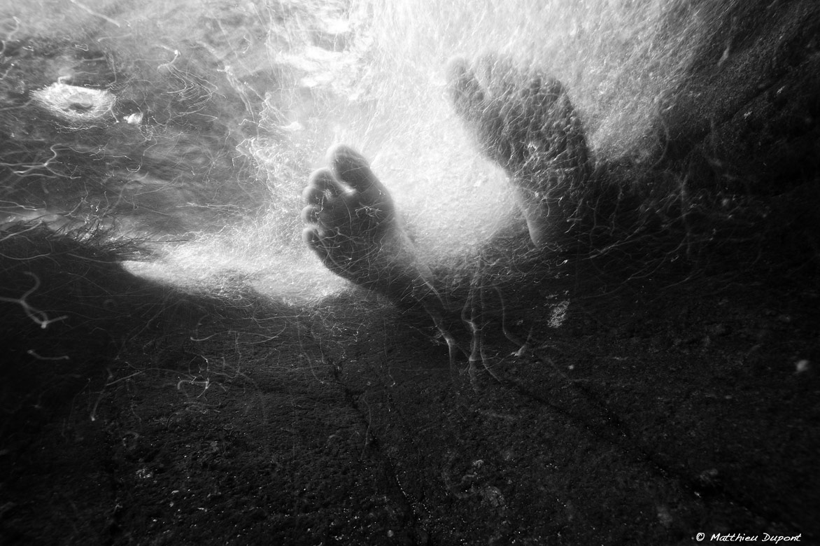 Photo sous l'eau en noir et blanc de pieds dans le courant, par Matthieu Dupont