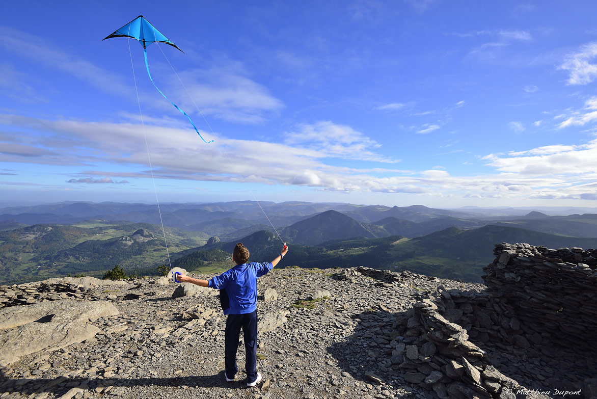 Enfant jouant avec son cerf-volant devant le superbe panorama du sommet du Mont Mézenc en Ardèche. Une photo de Matthieu Dupont