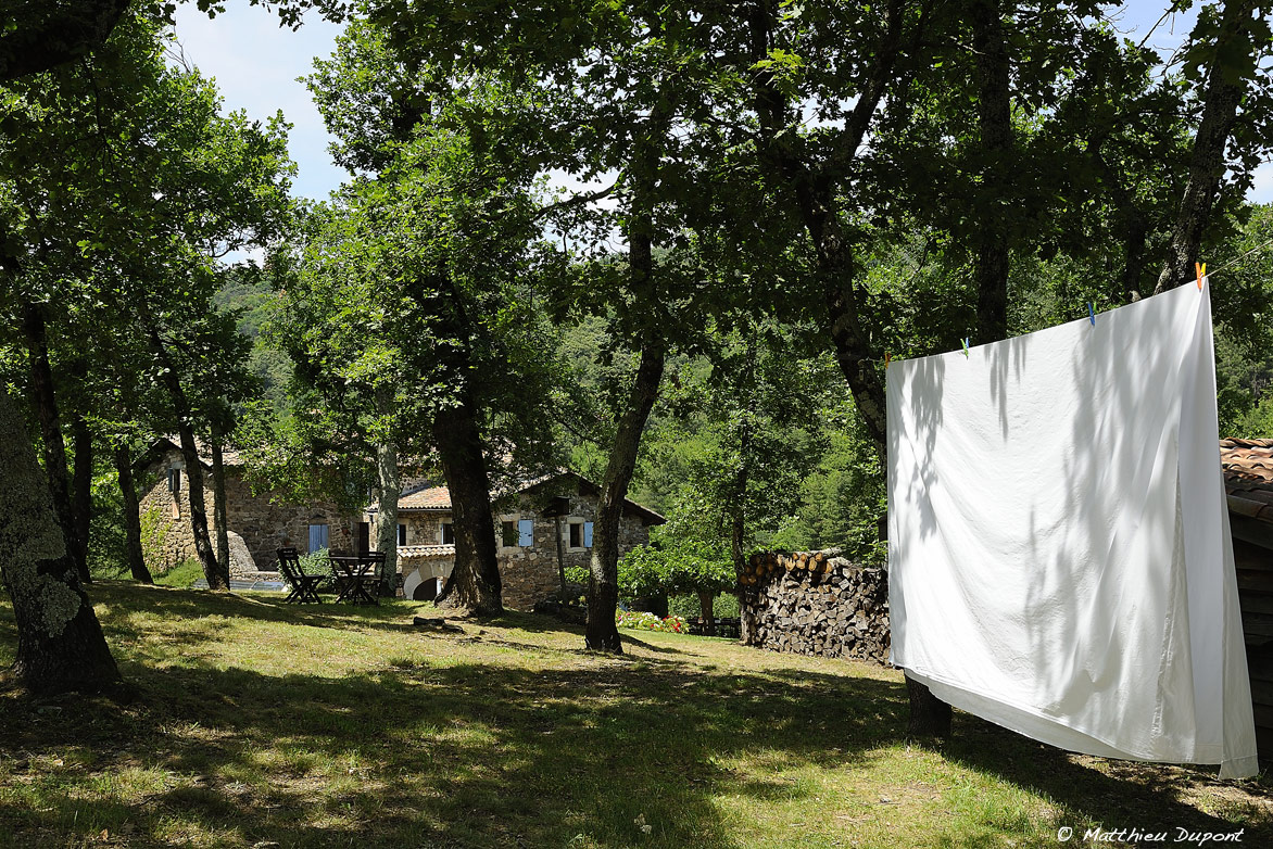 LEs draps blancs sèche au soleil dans le jardin de cette vieille bâtisse ardéchoise