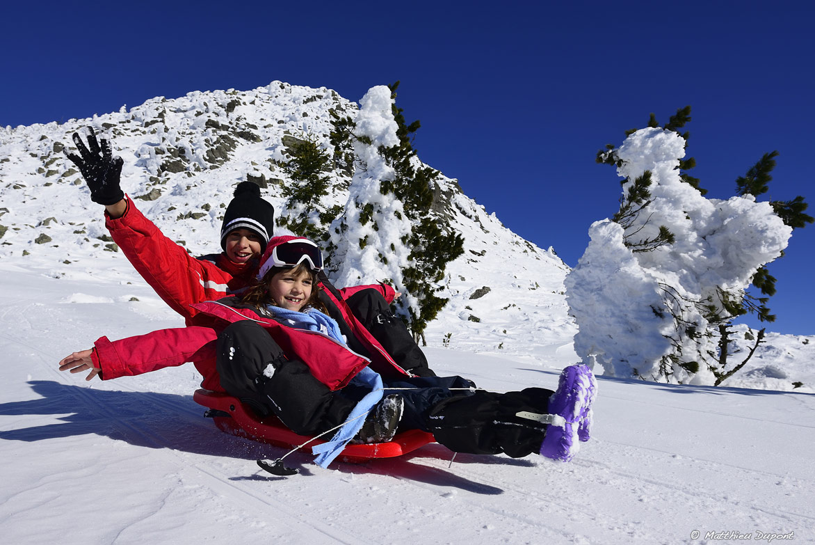 Deux enfants descendent en luge les pentes du Mont Mézenc en Ardèche. Une photo de Matthieu Dupont